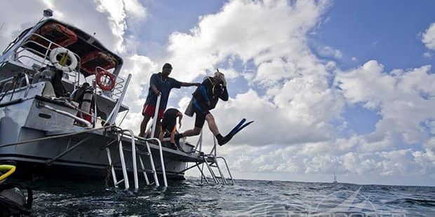 Tourists jumping off a sailboat to snorkel in ocean