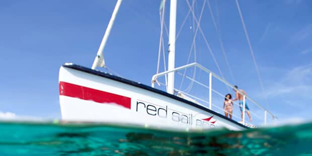 White sailboat with red stripe in the ocean