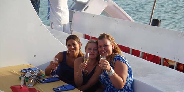 3 tourists drinking glass of champagne in sailboat