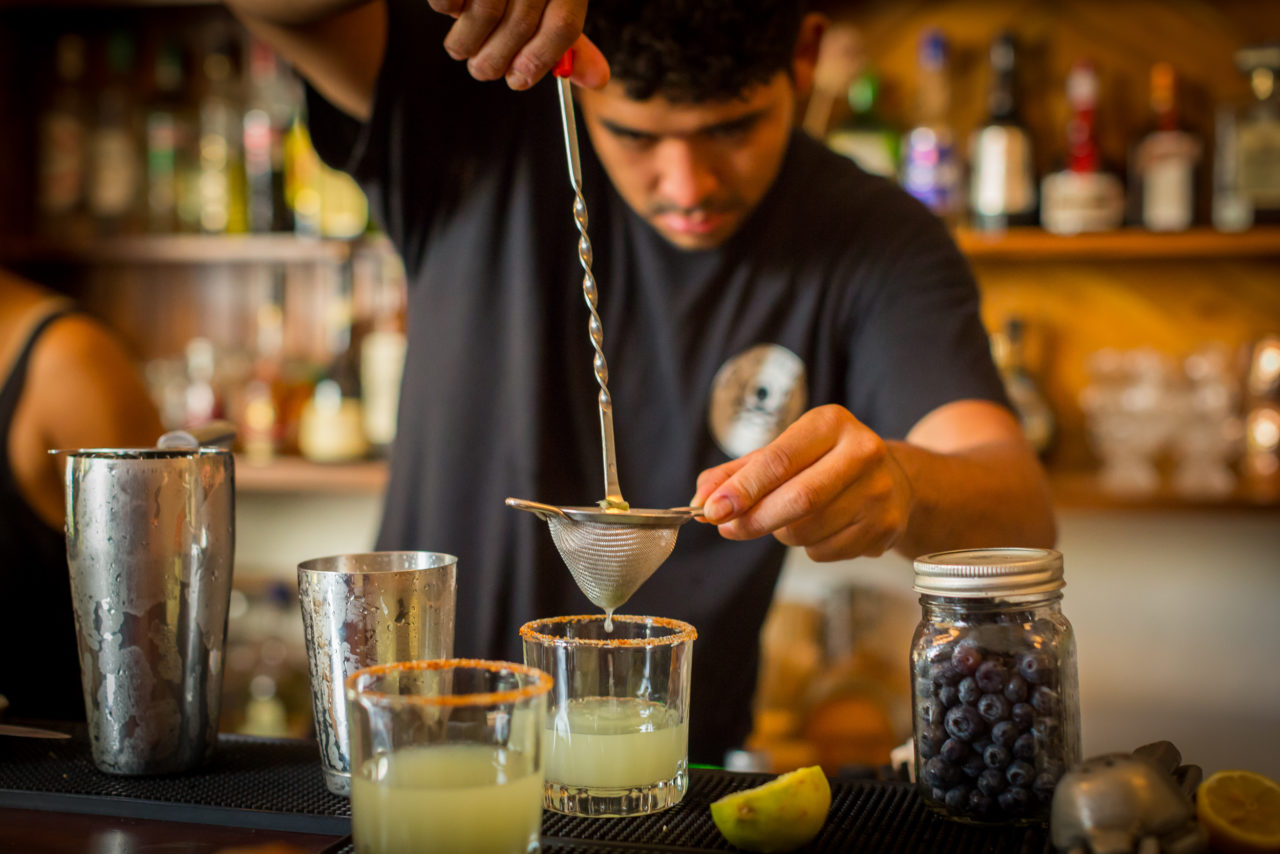 Bartender straining tequila into a drink. 